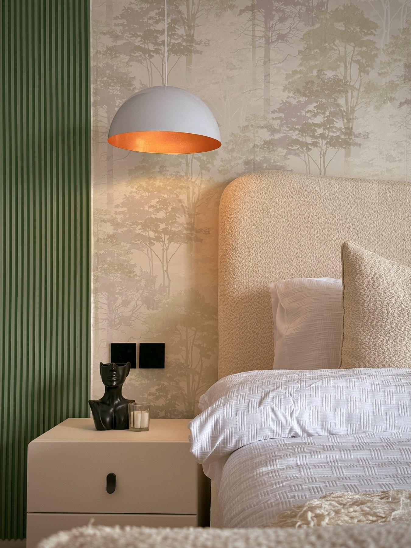 A bedside table and pendant lamp against the green panelling